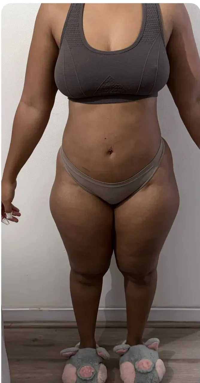 Mujer con top gris y pantuflas sobre un piso de madera.